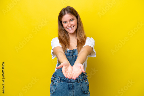 Obraz na plátně Young caucasian woman isolated on yellow background holding copyspace imaginary