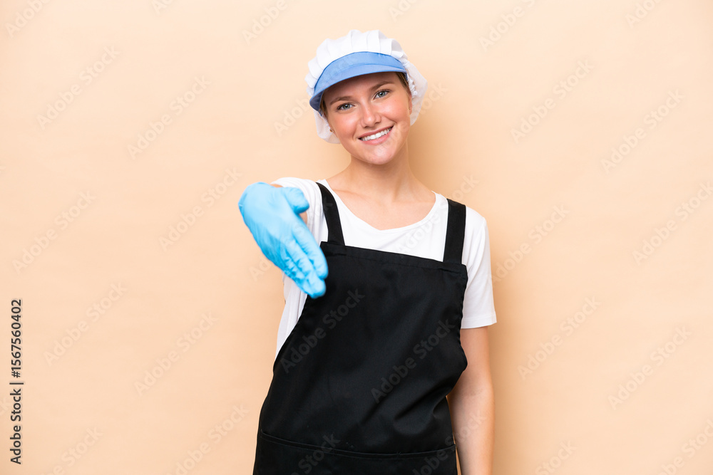Fishmonger caucasian woman wearing an apron and holding a raw fish isolated on beige background shaking hands for closing a good deal Fishmonger caucasian woman wearing an apron and holding a raw fish isolated on beige background shaking hands for closing a good deal
