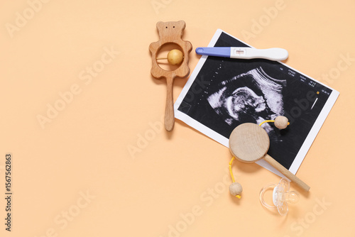 Composition with baby rattles, sonogram image, pregnancy test and nipple on o...