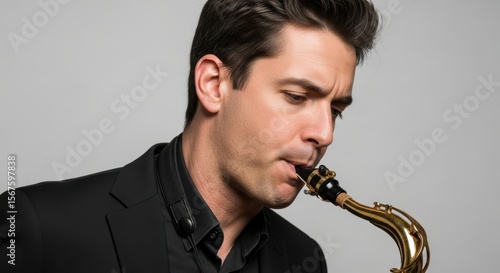 Young caucasian male saxophonist playing brass instrument in black suit