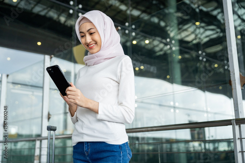 Canvas Print Muslim asian businesswoman traveler holding boarding pass ticket, passport and smartphone at the airport terminal with her luggage