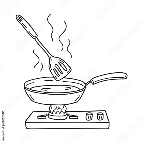 A spatula lying on a stovetop next to a frying pan
