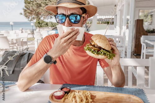 Fotografie Man disgusted by burger, possibly due to food poisoning or spoiled ingredients i
