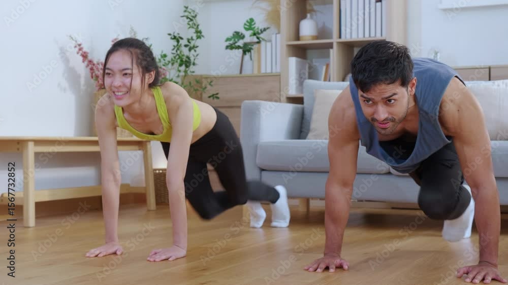 Happy young asian couple workout with doing mountain climbers exercise together in living room at home, smiling and energetic fitness training and cardio routine, motivation for health and wellbeing. Happy young asian couple workout with doing mountain climbers exercise together in living room at home, smiling and energetic fitness training and cardio routine, motivation for health and wellbeing.