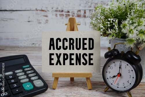 Accrued Expense text with alarm clock and calculator on wooden background