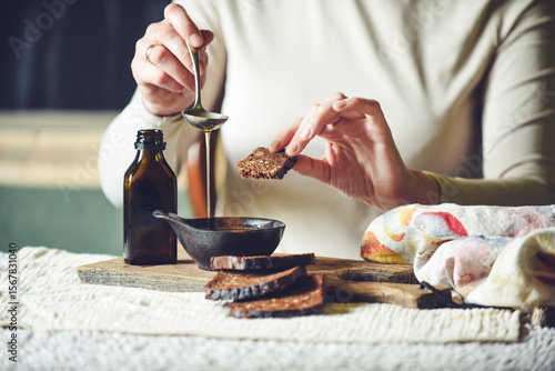 Woman's hands pouring freshly pressed homemade oil into a bowl, emphasizing traditional culinary practices and healthy eating. Rustic setting.