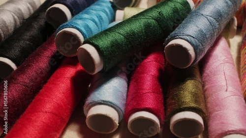 Close-up of colorful sewing thread spools highlighting vibrant textures and rich fabrics in a creative workspace