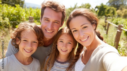 Happy family taking a selfie during a picnic in a sunny green park, parents and children smiling and enjoying nature, space on right for text