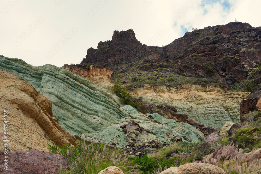 Fototapeta premium Colorful volcanic rock formations known as 'Los Azulejos' in Veneguera, Gran Canaria. A unique natural landscape shaped by minerals, erosion, and volcanic history
