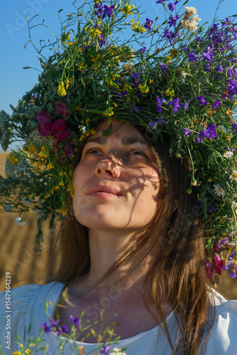 Portrait of a girl in a white dress, Slavic appearance with a wreath of wild flowers on her head.