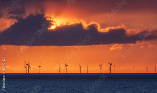 Stunning sunset over the sea near Denmark, captured from a cruise ship. Wind turbines silhouette the horizon under vibrant red and orange skies.