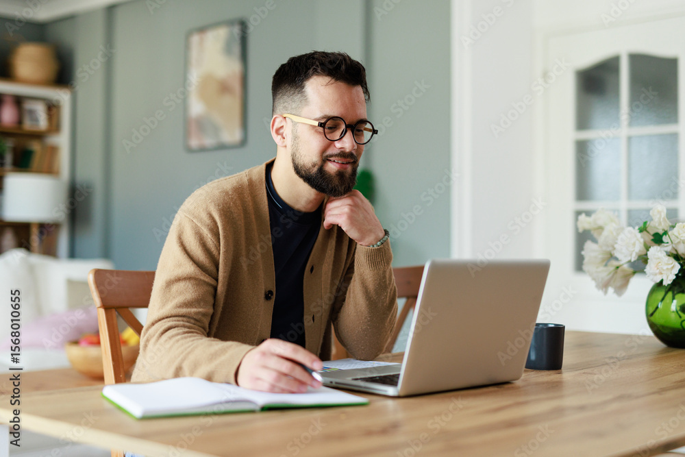 Young Caucasian Man Working Remotely in a Cozy Home Office Setting with Laptop and Notebook Young Caucasian Man Working Remotely in a Cozy Home Office Setting with Laptop and Notebook