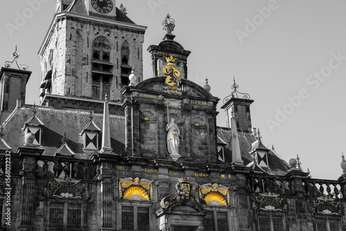 Black-and-white photo of Delft’s City Hall on Markt Square. Lady Justice, the Holland lion crest, and shell carvings keep their gold tones while the rest stays monochrome. 