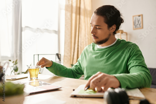 Obraz na plátne Young handsome man enjoying a cup of tea while working at home during a sunny af