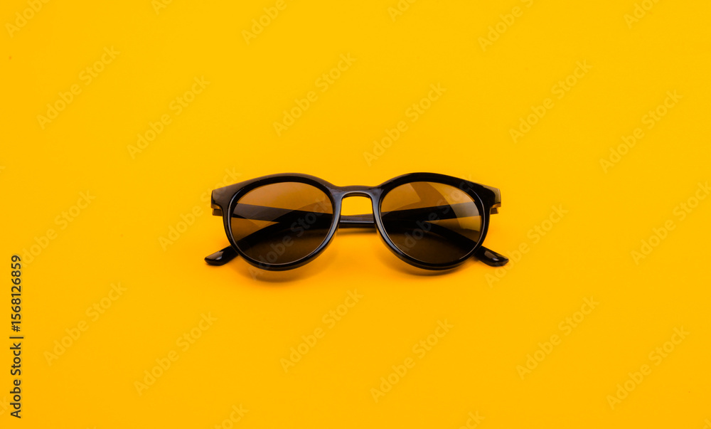 Stylish Black Sunglasses on Bold Yellow Background for Modern Fashion Concepts Stylish Black Sunglasses on Bold Yellow Background for Modern Fashion Concepts