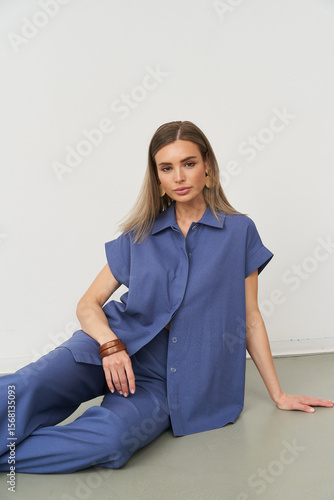 Fashionable female model poses in stylish blue outfit in studio setting