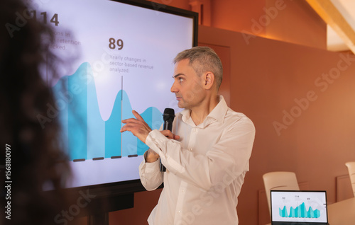 Fotografía A man asks his partner, pointing out a graph on the screen, during a colloquium