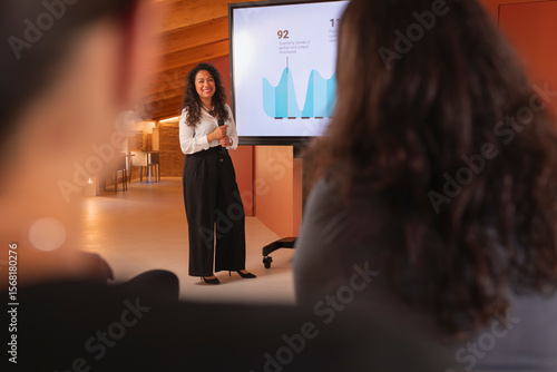A woman with Latin features shows a report with data, during a colloquium talk in the office
