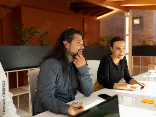 Work colleagues, talk about aspects of their work, during a meeting in the office