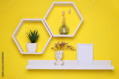 Shelf with empty photo frame and wall decor. Yellow background. Mockup for design