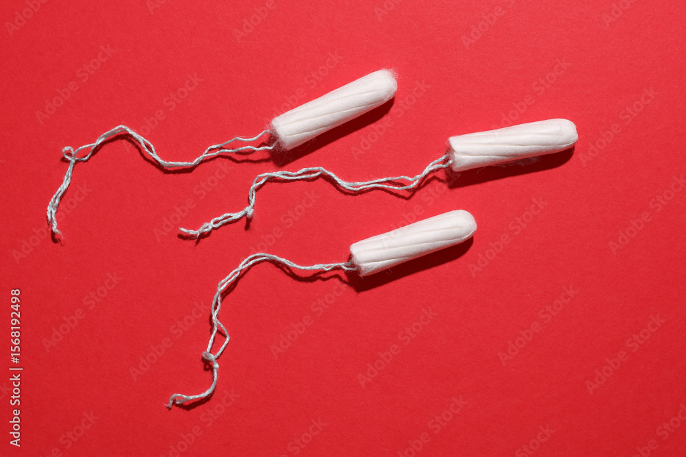 Tampons for feminine intimate hygiene on red background. Menstruation, critical days, female cycle Tampons for feminine intimate hygiene on red background. Menstruation, critical days, female cycle