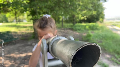 A little girl looks through a telescope on the observation deck. Close-up. Summer walk to the sights. Europe