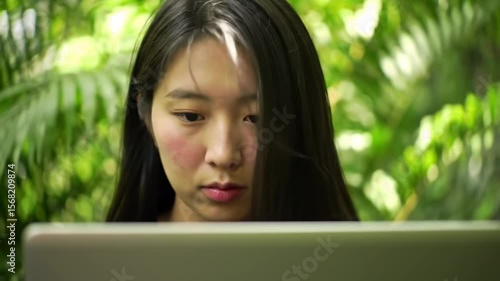 Young woman working on laptop outdoors