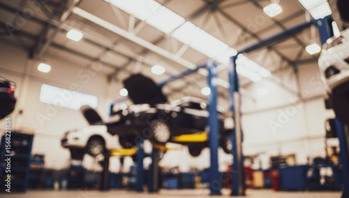 Auto repair shop with cars on lifts and mechanic working.