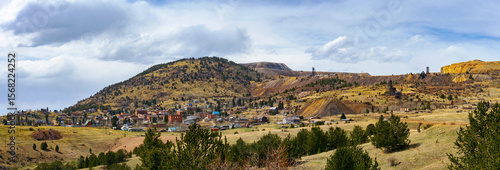 A wide view of Cripple Creek, Colorado, nestled against rolling hills and old mining structures. The historic town sits beneath a dynamic sky, its gold rush legacy still etched in the land.