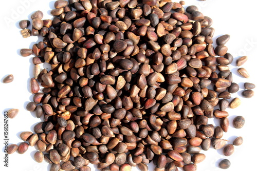 Konstfotografi There is a pile of unpeeled pine nuts on a white background.