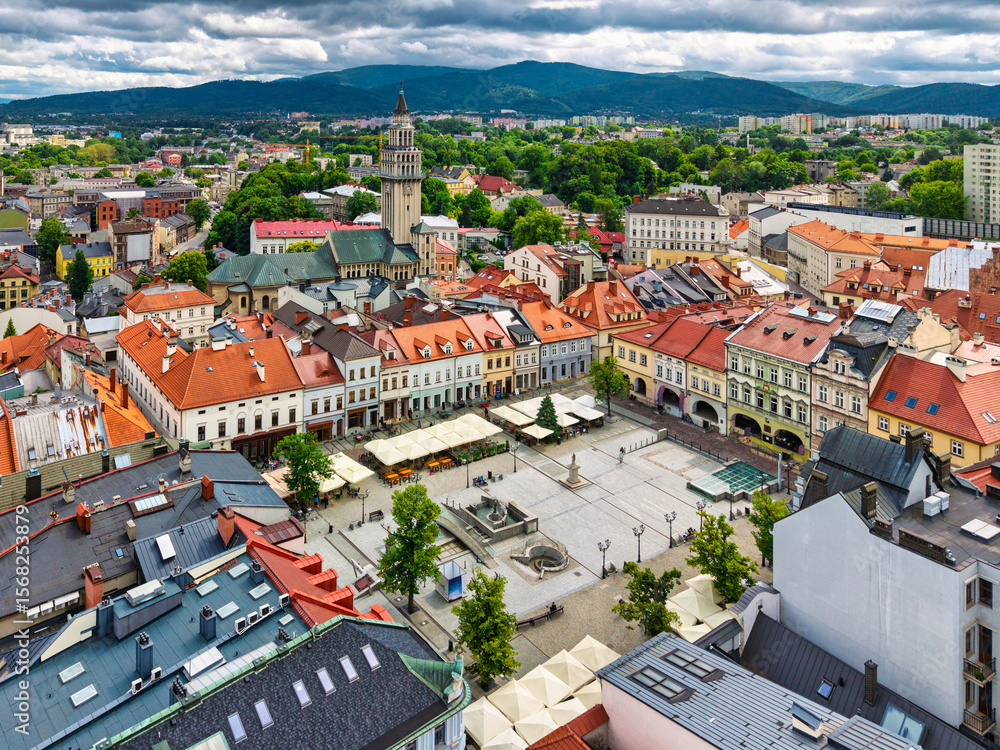 Naklejka premium Aerial view of historic town square in Bielsko-Biała, Poland with colorful buildings and mountains in the background.