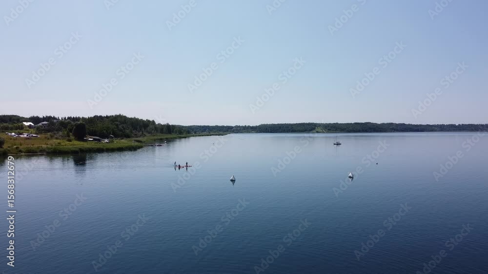 Paddle boarding on calm lake on sunny vacation day Paddle boarding on calm lake on sunny vacation day