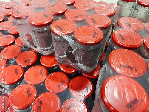 Large quantity of glass jars with red lids, some shrink-wrapped in bulk, perfect for food packaging, preservation, or commercial storage and distribution designs