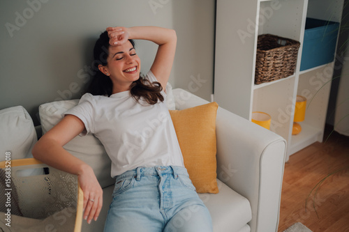 Фототапет Young woman relaxing on sofa after finishing laundry at home