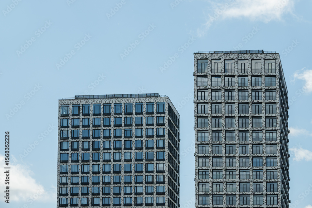 Fototapeta premium Two buildings with modern apartments at city. Architecture skyscrapers against blue cloudy sky.