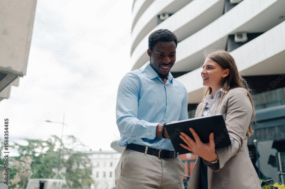 Fototapeta premium Smiling business colleagues using tablet in urban setting