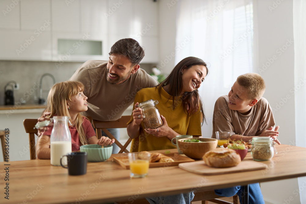 Young parents and their small kids talking while having breakfast in dining room. Young parents and their small kids talking while having breakfast in dining room.
