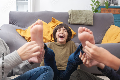 Laughing child gets tickled by family at home