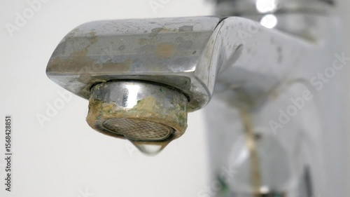 Water is dripping from a damaged faucet. The old faucet was covered with lime scale due to poor water quality and hard water. Useless use of water. Plumbing problems. 4k.
