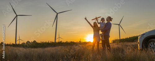 Family with son walking on field on wind farm. Happy Family and son playing at the Wind turbines generating electricity. Family time together.