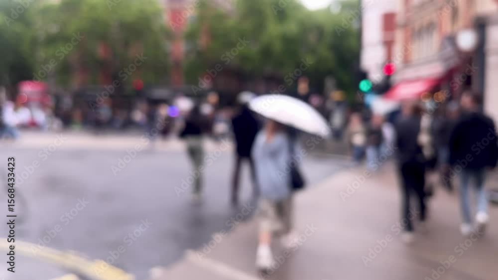 Blurred view of a rainy London street, with umbrellas, red double-decker buses, and pedestrians crossing beneath dripping trees, atmospheric and moody, defocused Blurred view of a rainy London street, with umbrellas, red double-decker buses, and pedestrians crossing beneath dripping trees, atmospheric and moody, defocused
