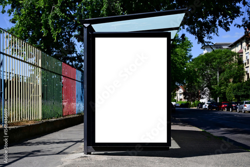 bus shelter at a busstop. blank billboard ad display. empty white lightbox sign. ad space. city transit station. glass structure. urban street setting. outdoor advertising concept.