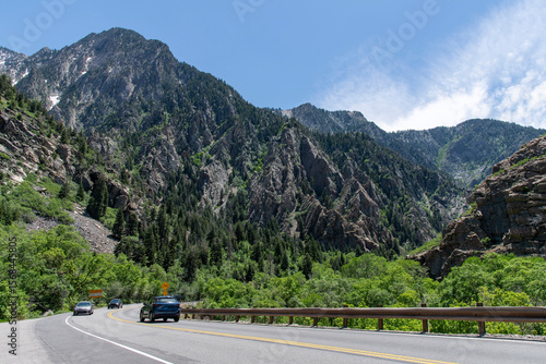 Road with cars through Cottonwood Canyon on Cottonwood Heights, Utah, US with rocky mountains in background against a blue sky