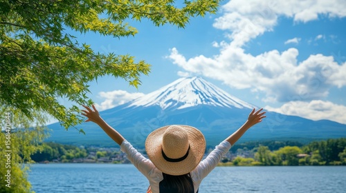 A happy tourist is enjoying the view of Mount Fuji at Lake Kawaguchiko in Japan. It's a beautiful spring or summer day, perfect for a Japan vacation.
