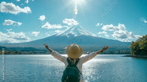 A happy tourist is enjoying the view of Mount Fuji at Lake Kawaguchiko in Japan. It's a beautiful spring or summer day, perfect for a Japan vacation.
