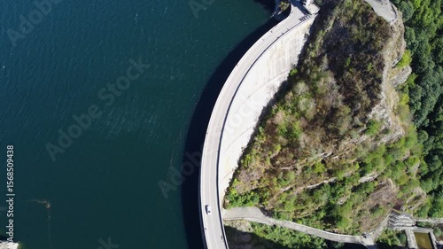 4K aerial footage of Vidraru Dam and Lake in Romania with a car crossing the dam on a sunny summer day
