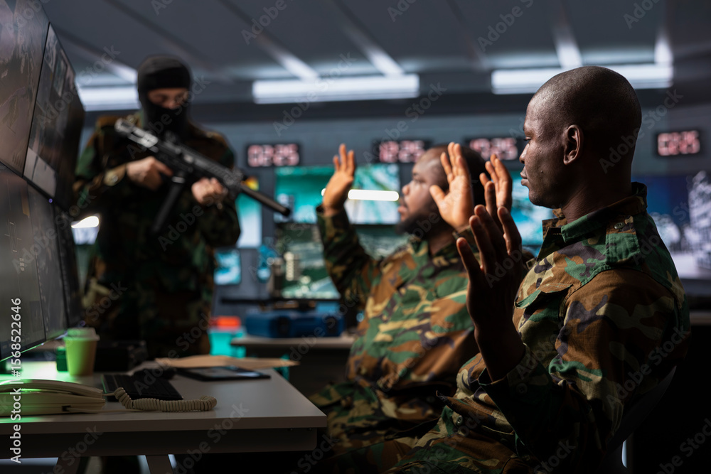 Obraz premium Dangerous terrorist threatening soldiers with rifles in command post. Insurgent using guns to control african american hostages during enemy base assault hijacking, during guerilla warfare armed