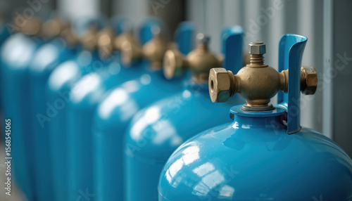Lineup of bright blue compressed gas cylinders, industrial, medical gases. Focus on brass valves, regulators. Oxygen, nitrogen, argon, CO2 for welding, healthcare, laboratory applications. High