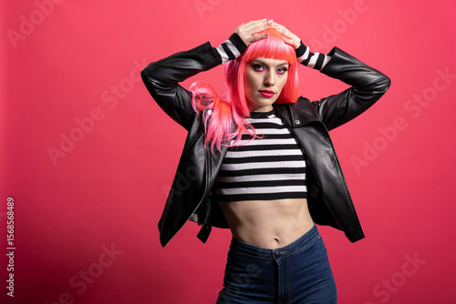 Schilderij op canvas Trendy model with pink hair and bold jacket embraces confident rocker style against isolated background