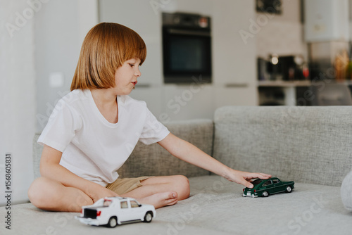 Canvas Print Young boy playing with toy cars in a cozy living room, expressing joy and creativity while enjoying his playtime at home with a relaxed atmosphere